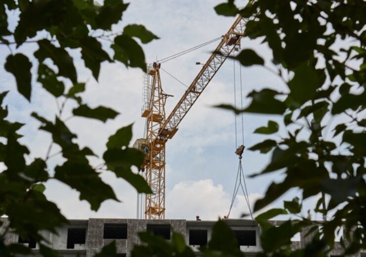 Industrial,Tower,Crane,Framed,By,Green,Tree,Leaves,Outdoors