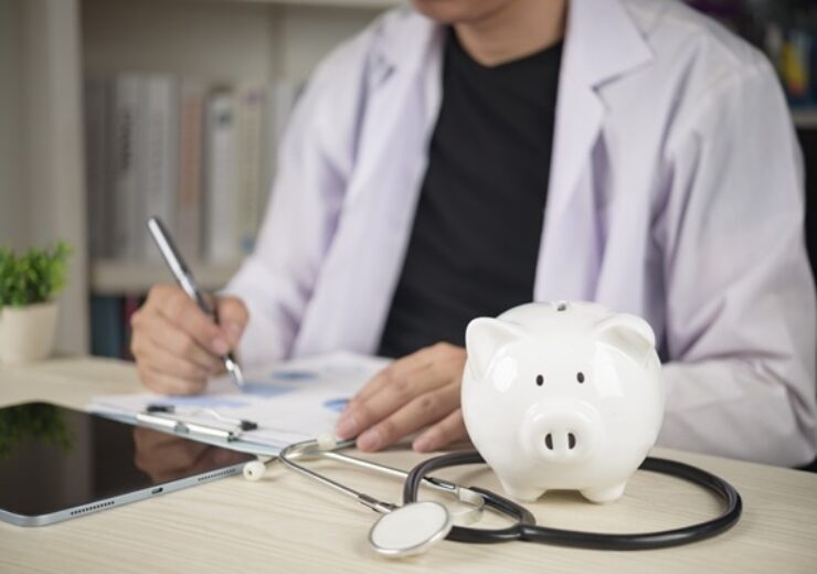 Doctor,With,Stethoscope,And,White,Piggy,Bank,On,Desk,,Concepts
