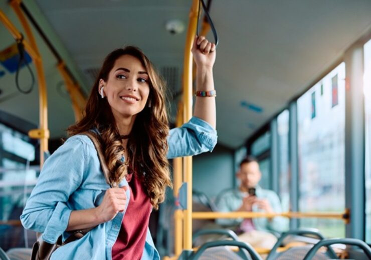 Young,Smiling,Woman,Holding,Onto,A,Handle,While,Traveling,By