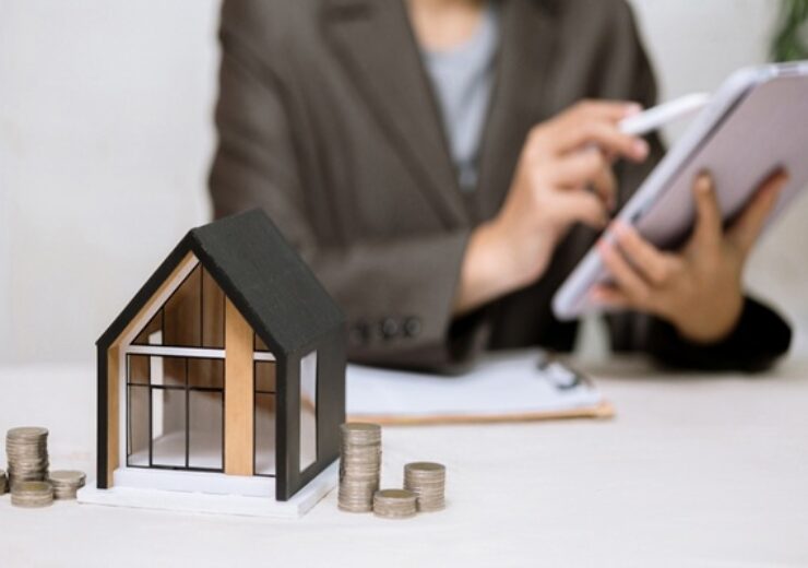 A,Model,House,And,Stacks,Of,Coins,Sit,On,A